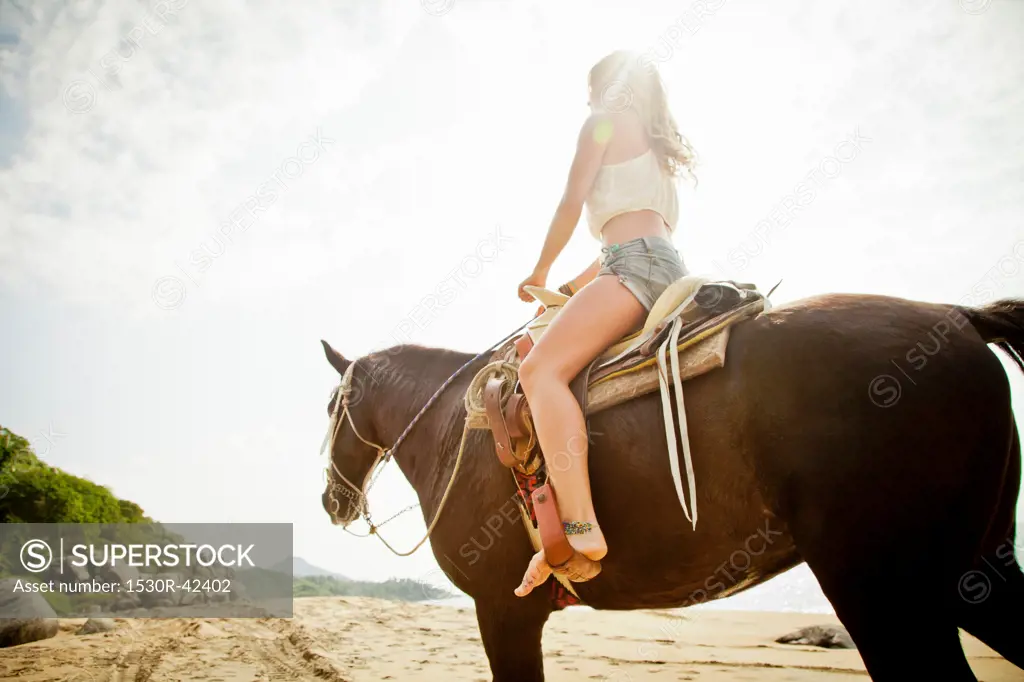 Young woman riding horse on beach