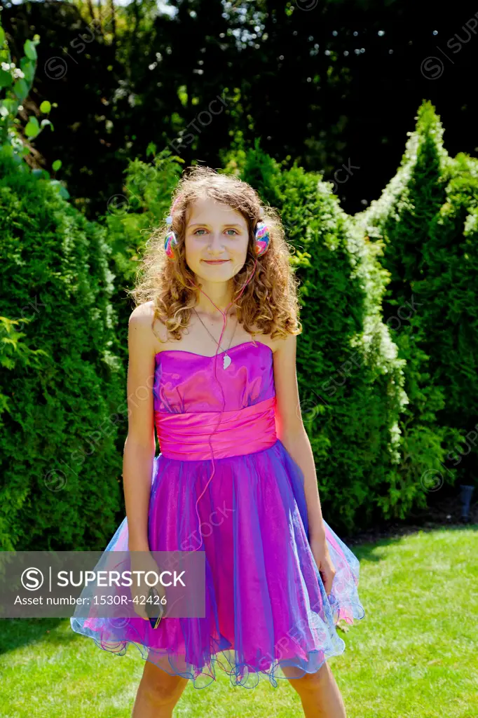 Teen girl in party dress listening to music outdoors