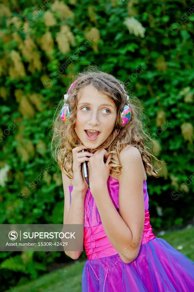 Teen girl in party dress listening to music outdoors