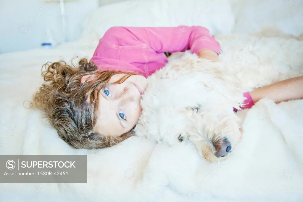 Teen girl cuddling dog on bed