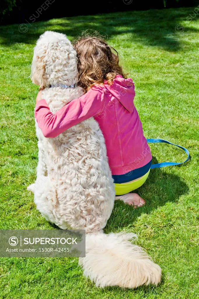 Teen girl with arm around white dog