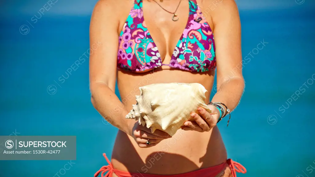 Woman in bikini holding shells