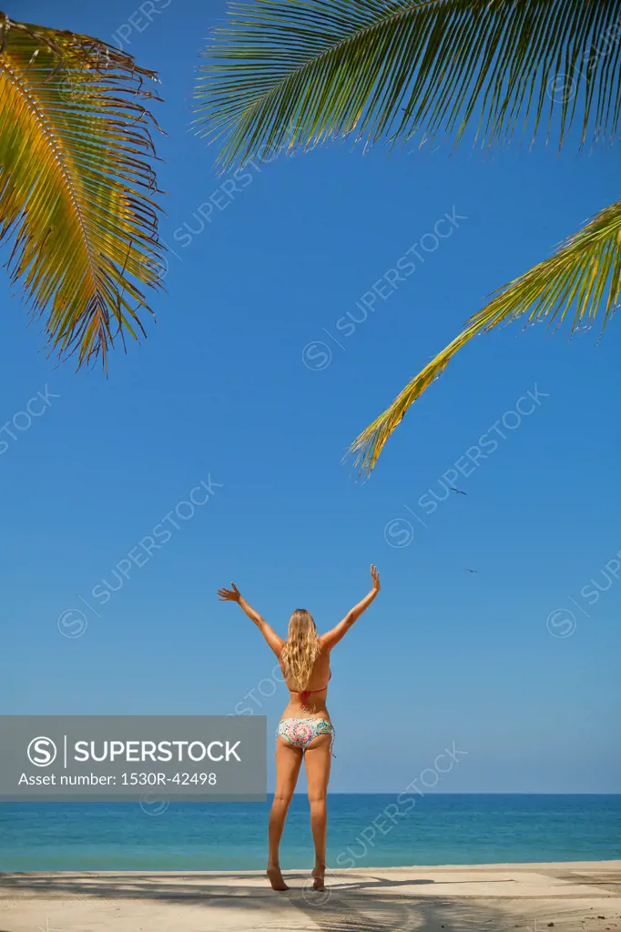 Woman in bikini jumping on beach