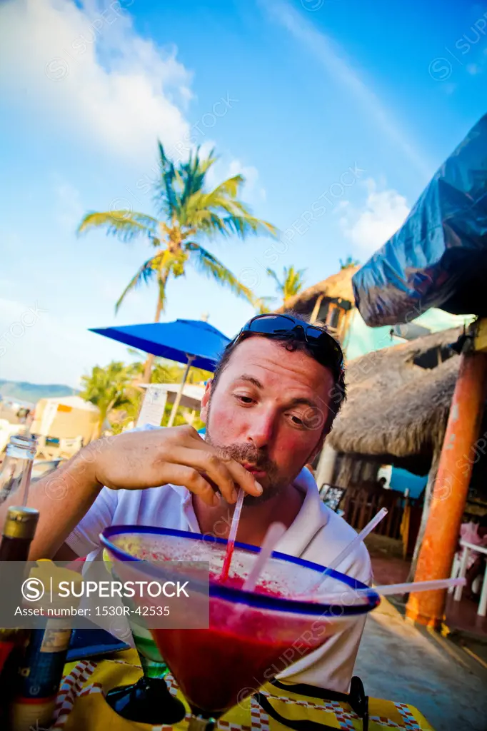 Man drinking oversized cocktail