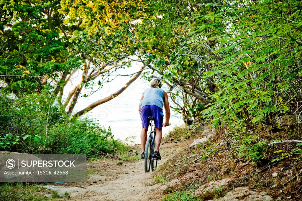 Man riding bicycle on path to beach