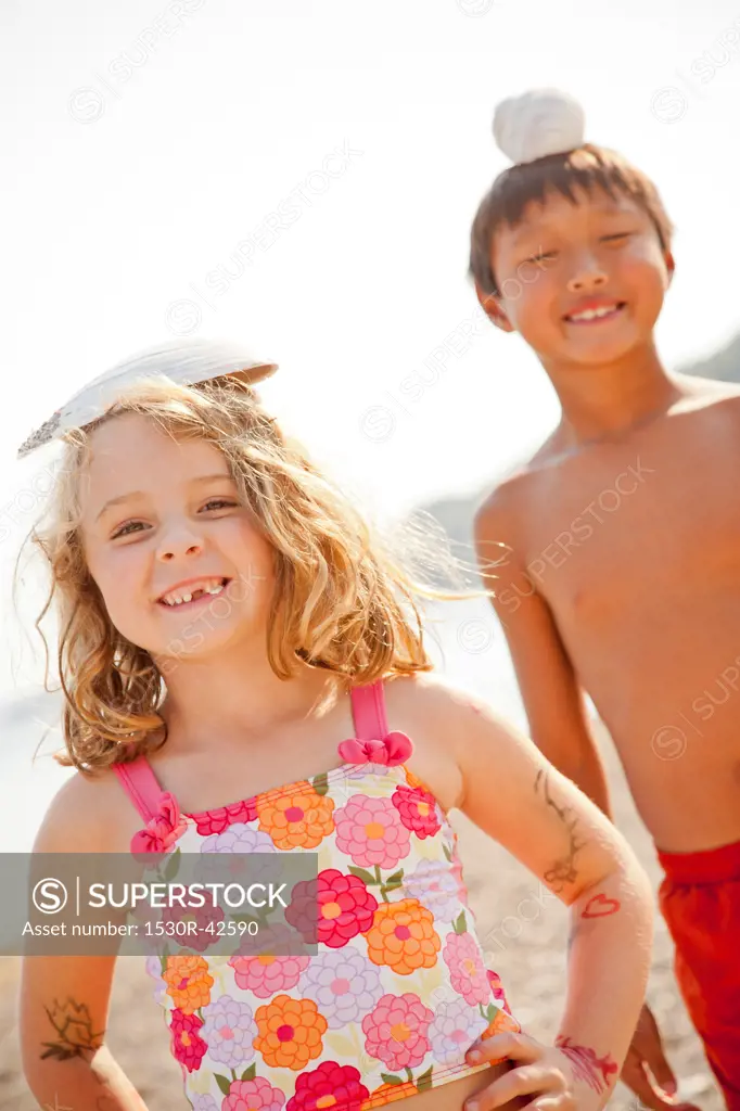 Young boy and girl balancing shells on their heads