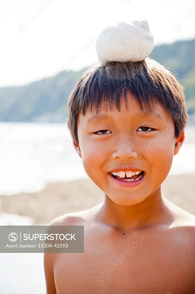 Boy with moonsnail shell on his head