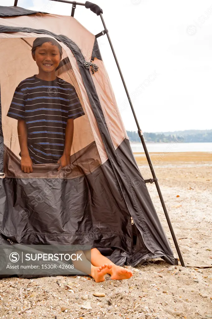 Young children playing in tent on beach