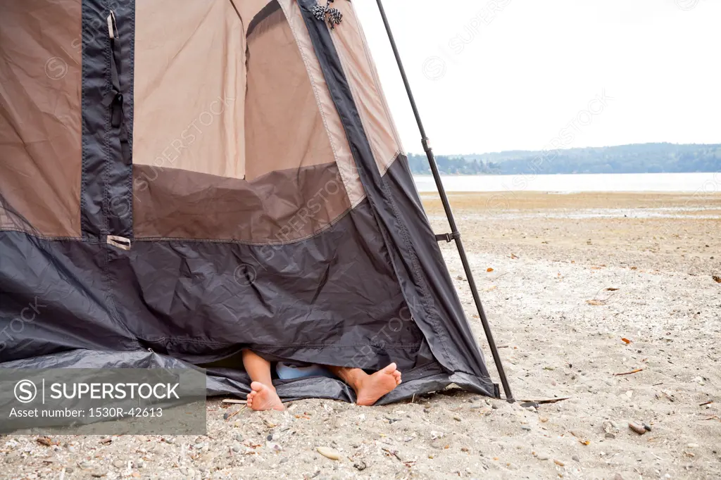 Child's feet sticking out of tent on beach