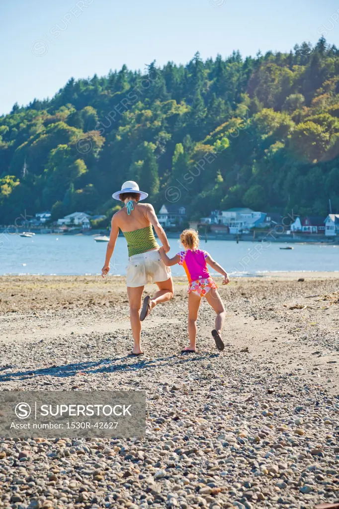 Mother and daughter walking down beach