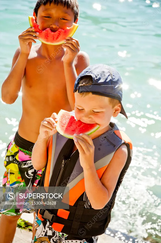 Young boys eating watermelon by lake