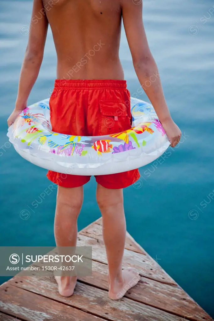 Young boy wearing float ring on dock