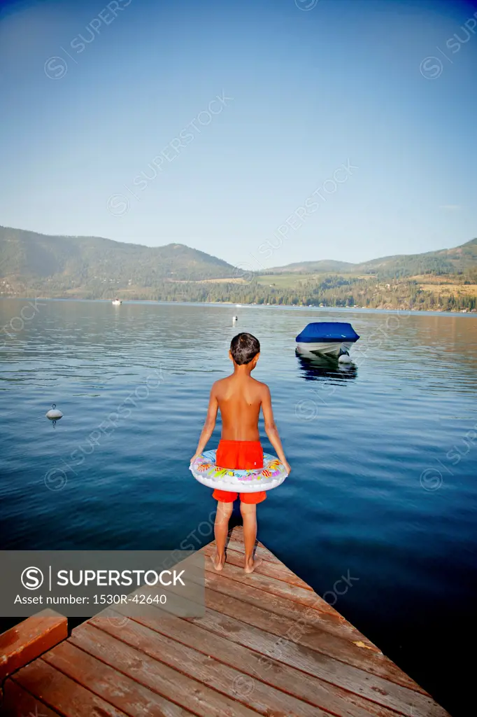 Young boy wearing float ring on dock