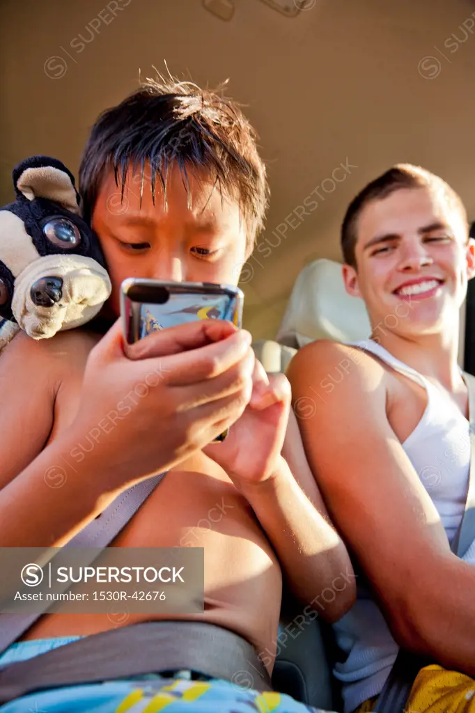 Boys in backseat of car with phone