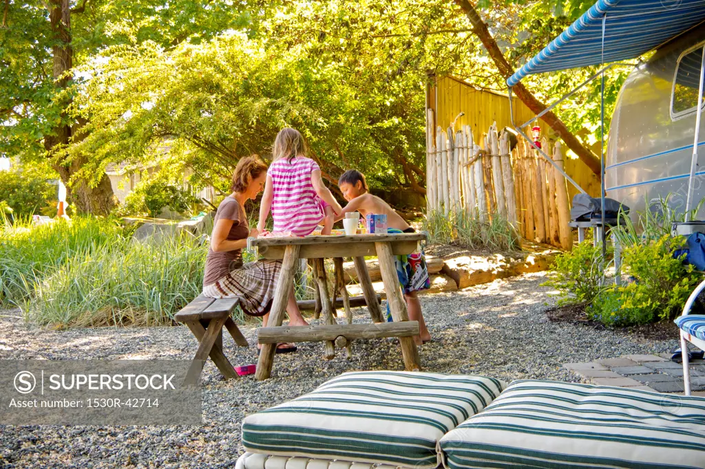 Woman playing board game with children at picnic table