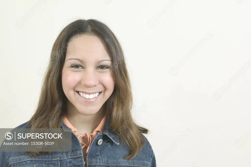 Studio portrait of young Hispanic teenage girl, smiling.  