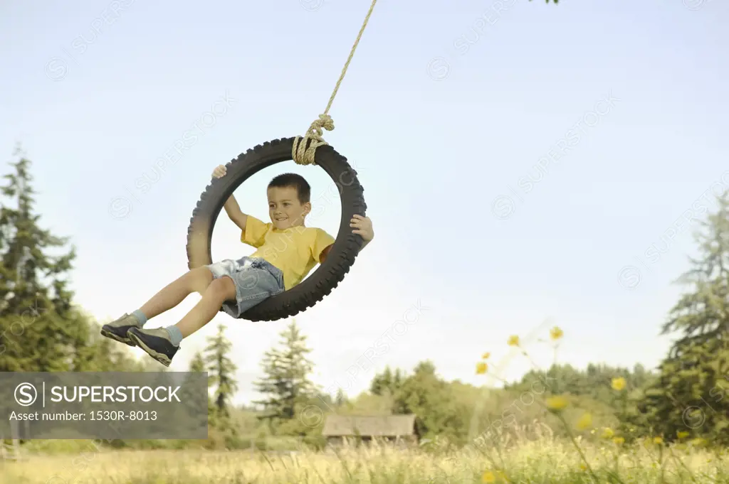 Boy riding on a tire swing.