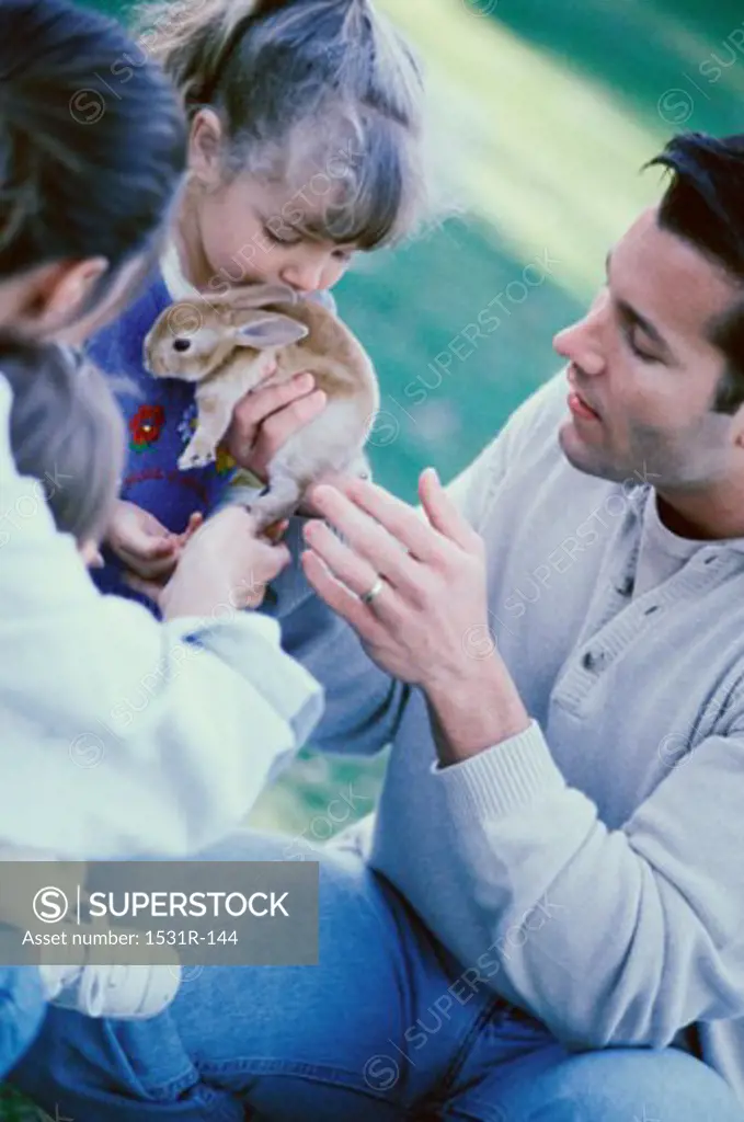 Father and his two children holding a rabbit