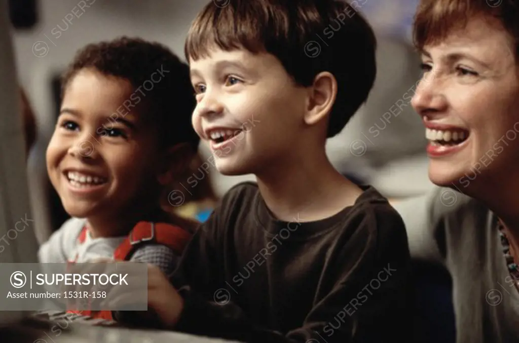 Female teacher in front of a computer monitor with two boys