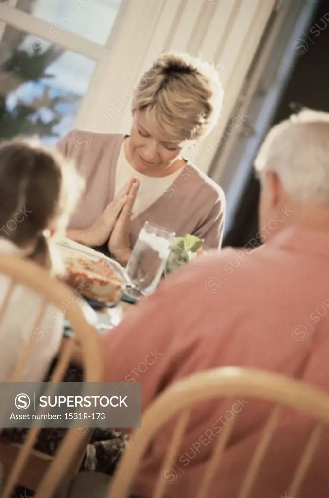 Family sitting at the dining table praying