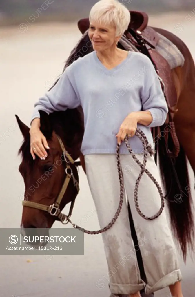 Senior woman standing with a horse