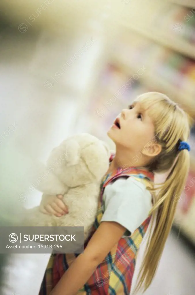Side profile of a girl holding a stuffed teddy bear