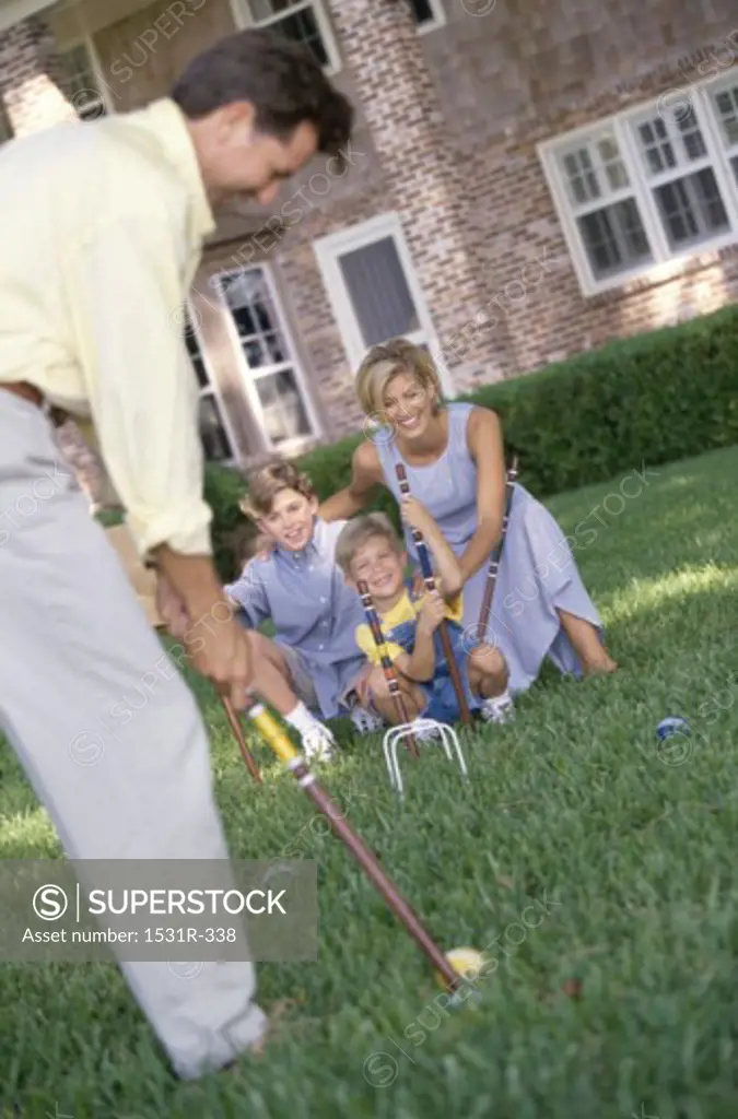 Mother and father playing on a lawn with their two children