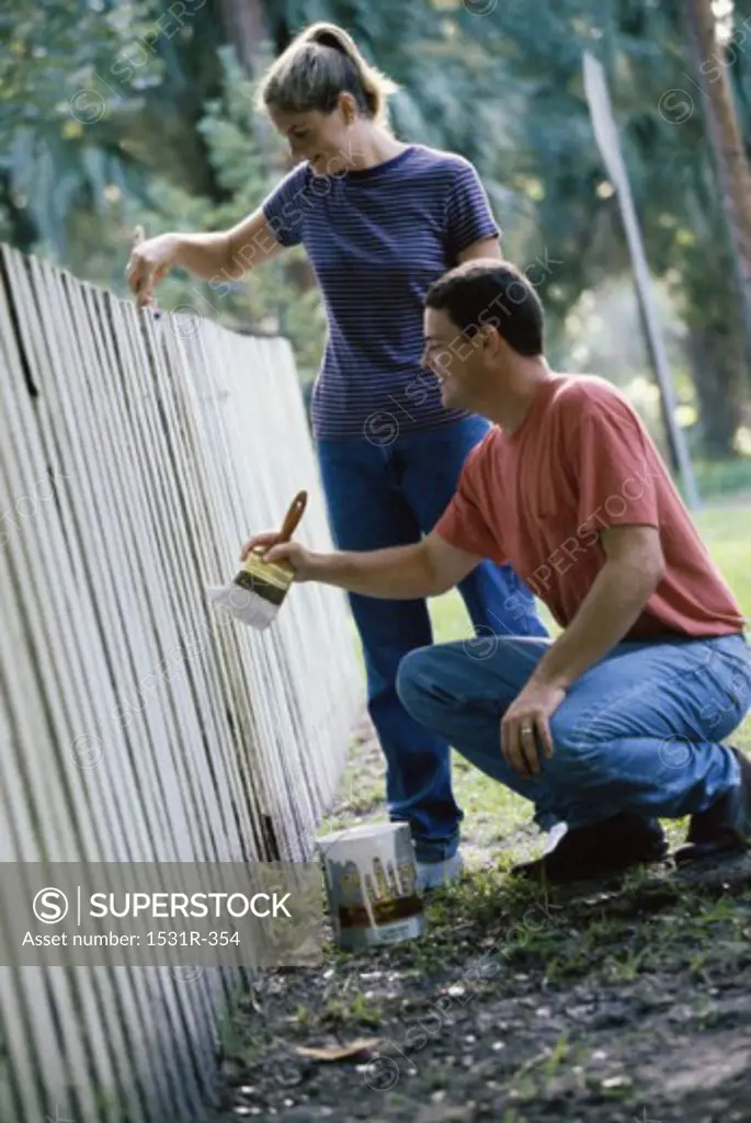 Young couple painting a fence
