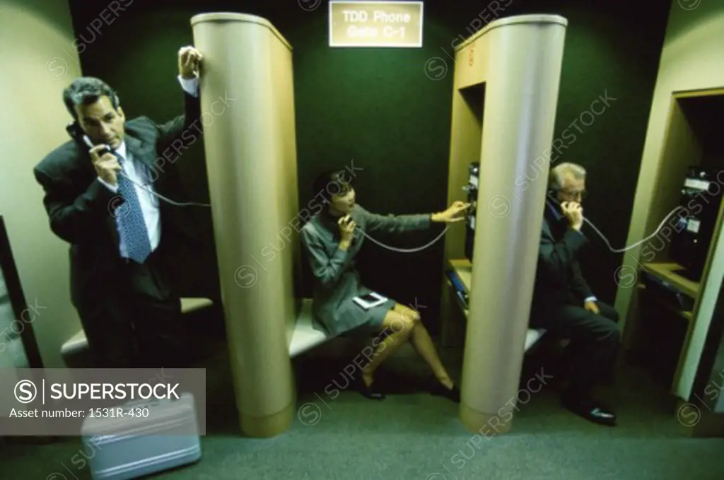 Business executives talking on pay phones