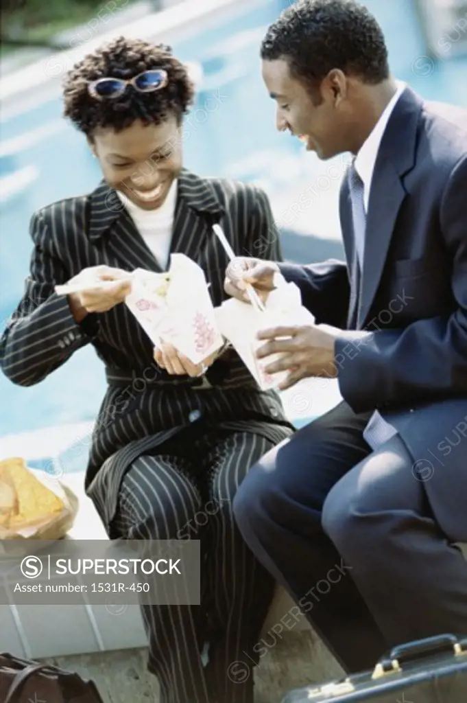 Businesswoman and a businessman eating Chinese takeout food