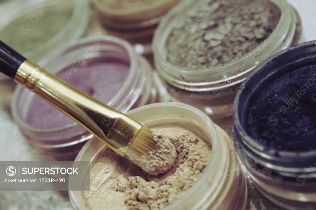 Close-up of open containers of cosmetics and an applicator brush
