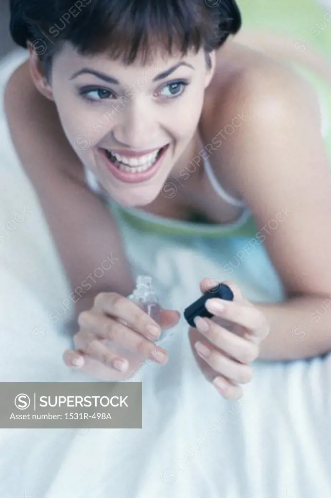 High angle view of a young woman applying nail polish