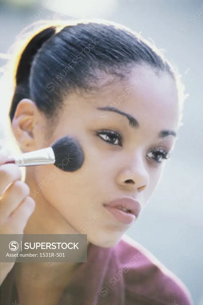 Close-up of a young woman applying make-up