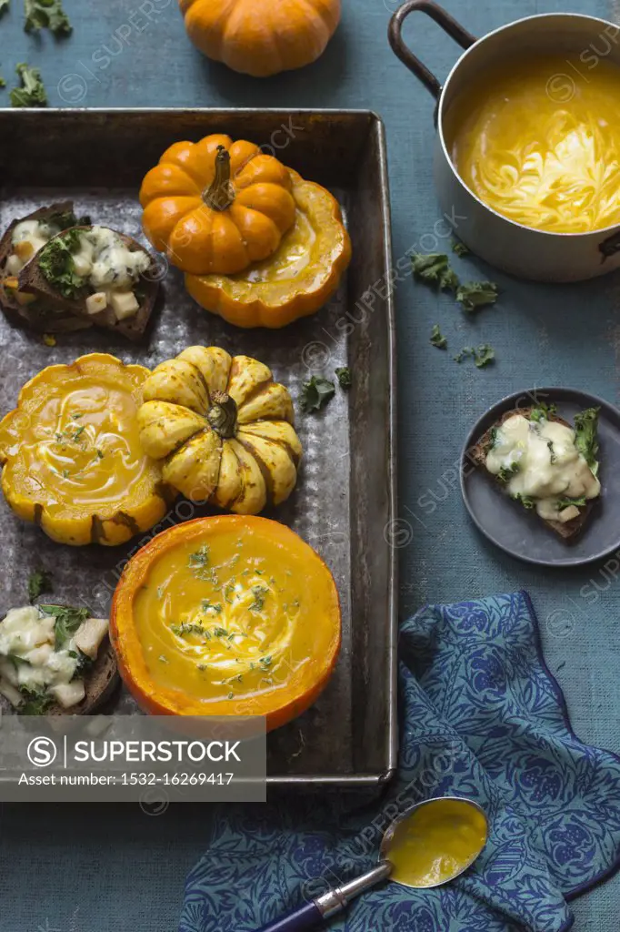 Pumpkin soup with rosmary and yogurt in small pumpkins, toasts with pears, kale and gorgonzola