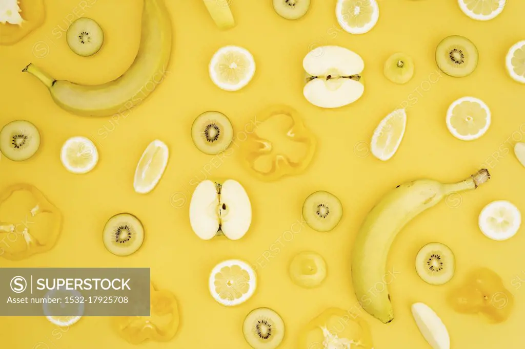 Various fresh fruits and vegetables arranged on yellow background