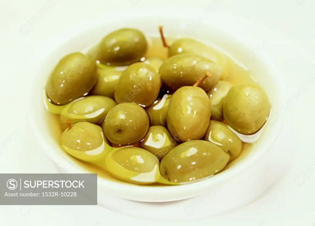 Pickled green olives in a small white bowl