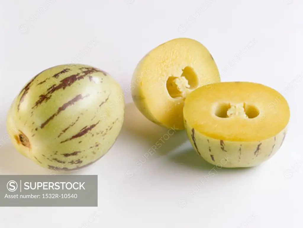 A pepino melon beside two pepino melon halves