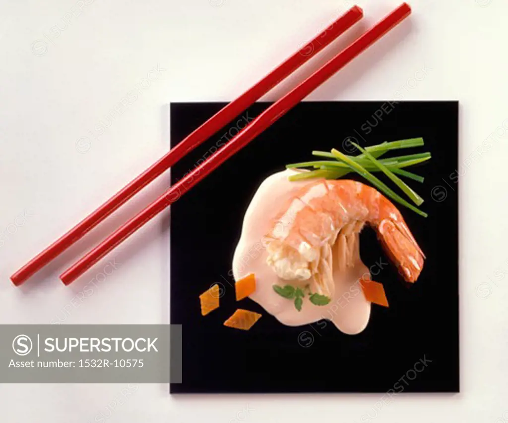 King prawn on black platter with red chopsticks
