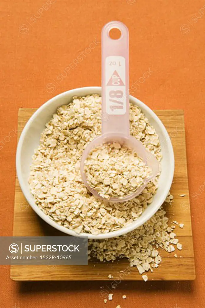 Rolled oats in a bowl with plastic measuring spoon