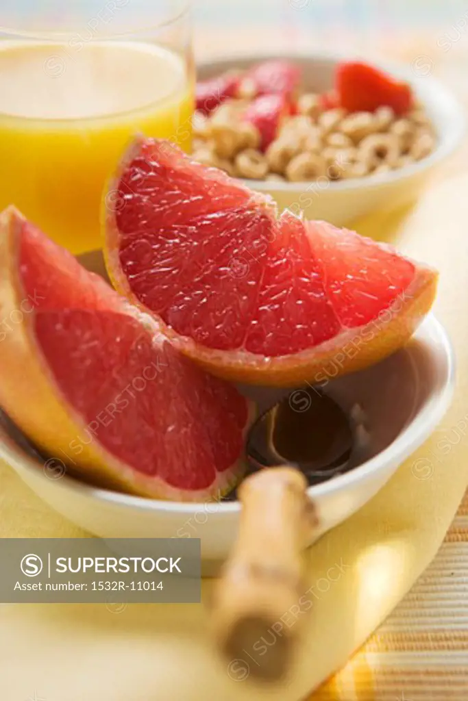 Grapefruit wedges in a bowl, cereal behind