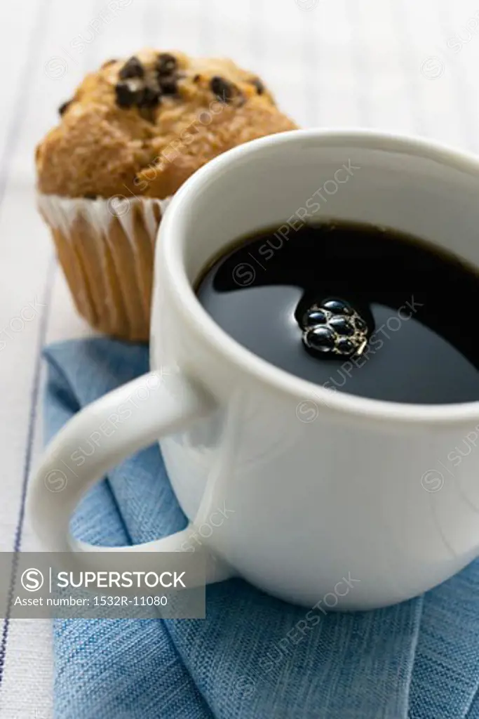 A cup of coffee with a muffin