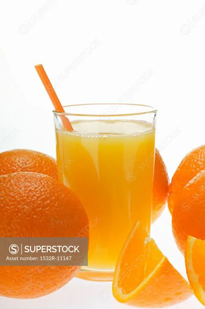 Orange juice in glass with straw among oranges