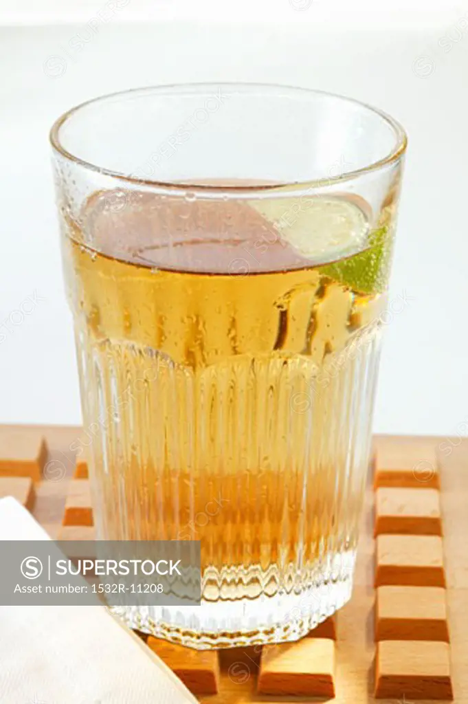 Apple juice with wedge of lime in glass