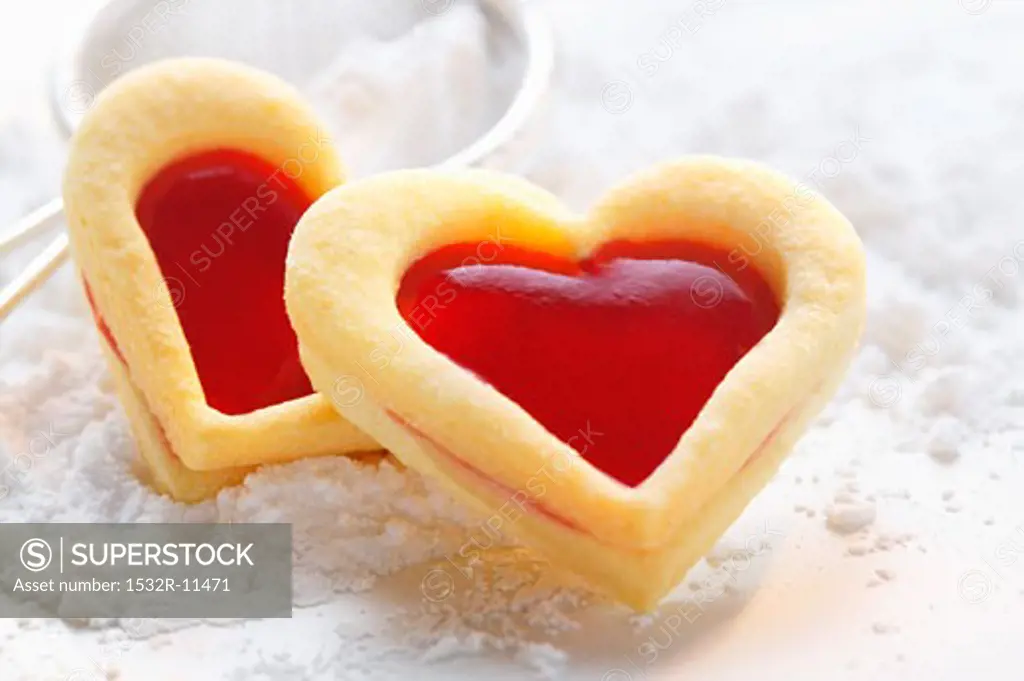 Sweet pastry hearts with raspberry jam on icing sugar (1)