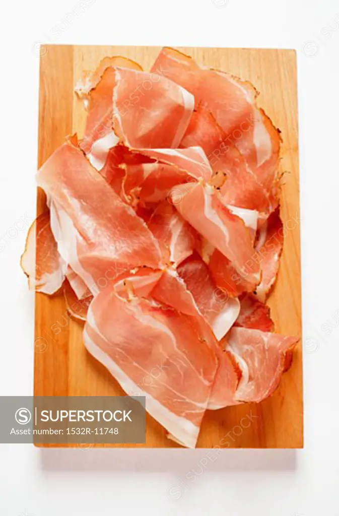 Slices of raw ham on chopping board