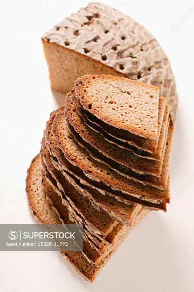 A quarter of a farmhouse loaf and slices of bread in a pile
