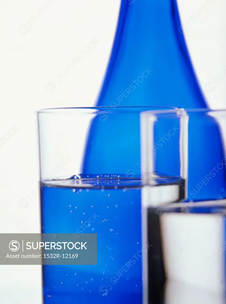 Two glasses of water in front of blue water bottle