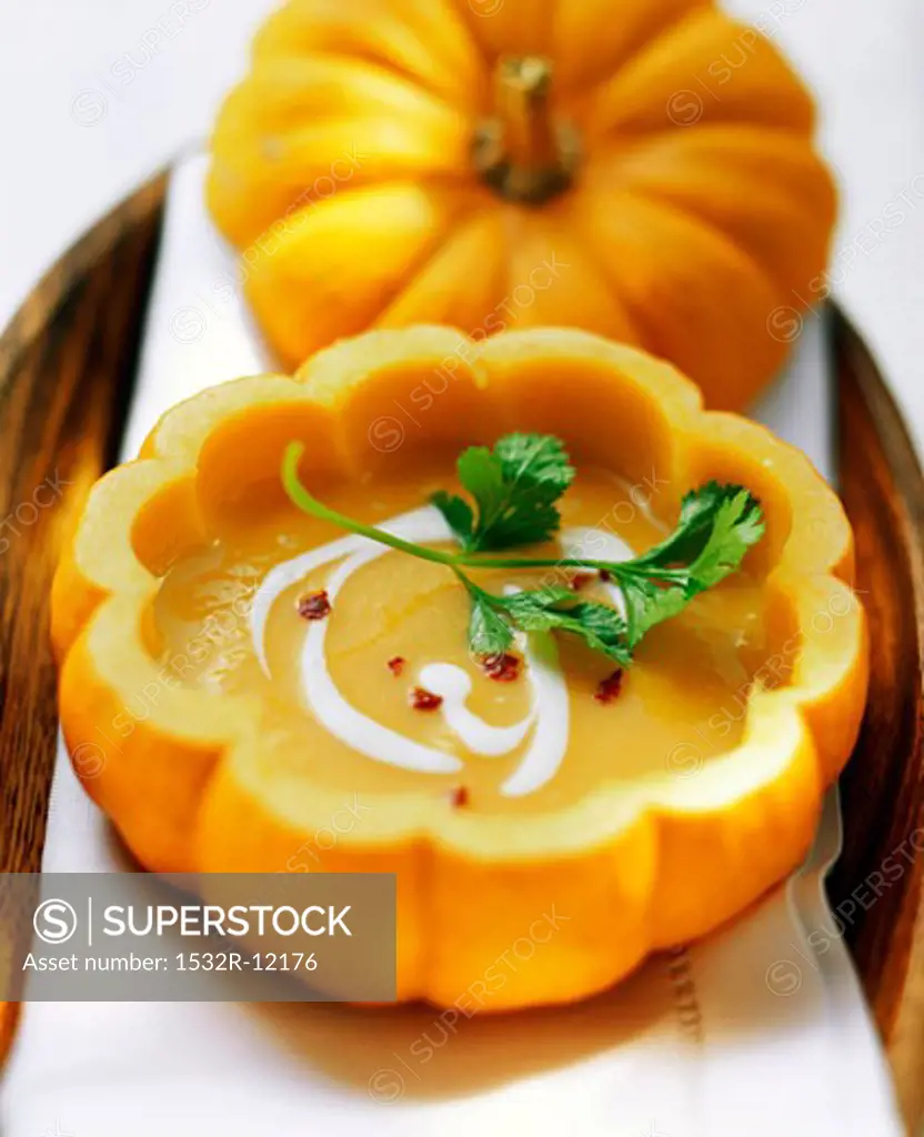 Pumpkin soup with sour cream and coriander served in pumpkin