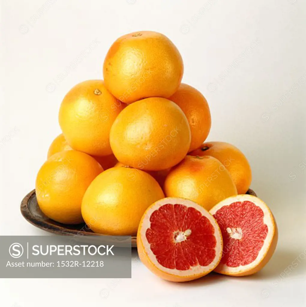 Pink grapefruits on plate, one cut open in front