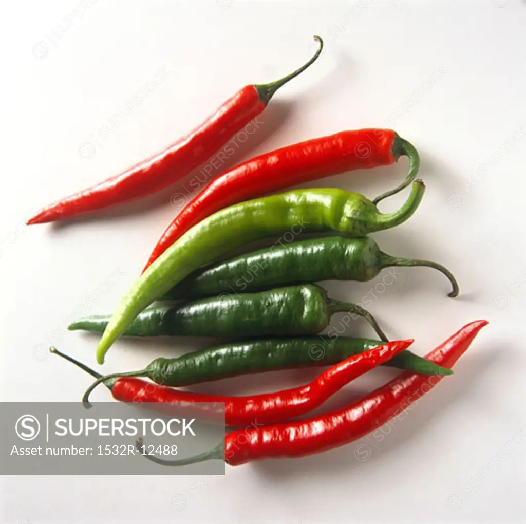 Four red and four green chili peppers on white background
